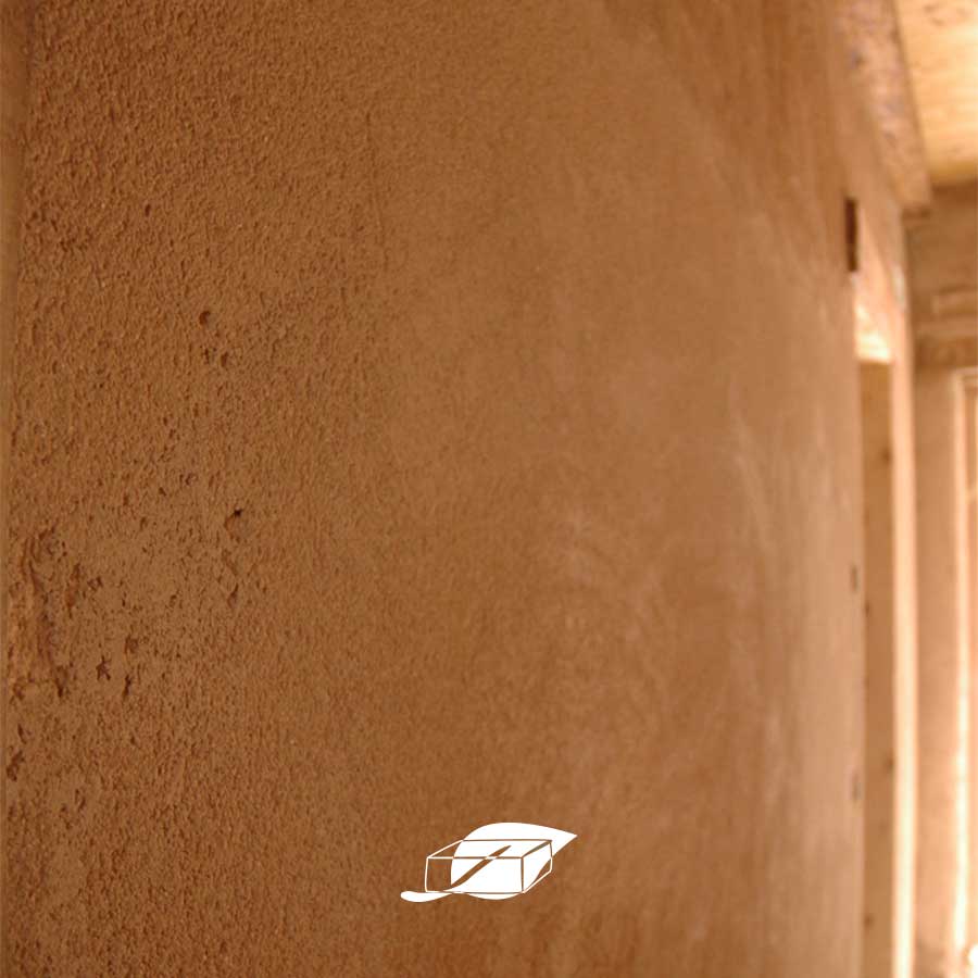 Parete con intonaco in argilla in un ambiente luminoso. Finitura naturale ed ecologica per interni salubri.