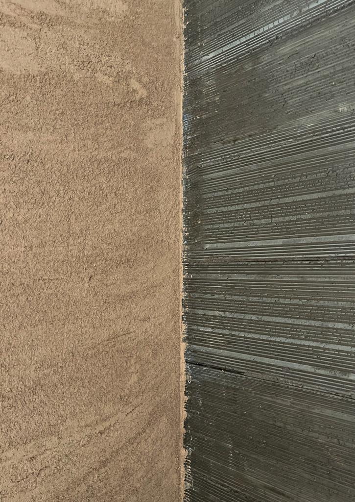 Dettaglio dell’angolo interno di una parete con pannello in argilla Clayboard e intonaco in terracruda applicato, in un intervento di bioedilizia.
