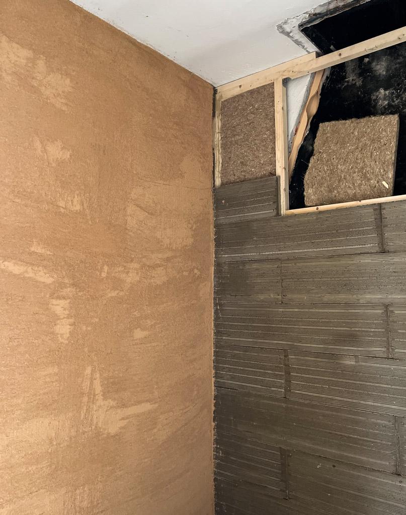 Sistema di isolamento naturale composto da pannelli in canapa e argilla Clayboard, con finitura in intonaco di terra cruda applicato a parete.