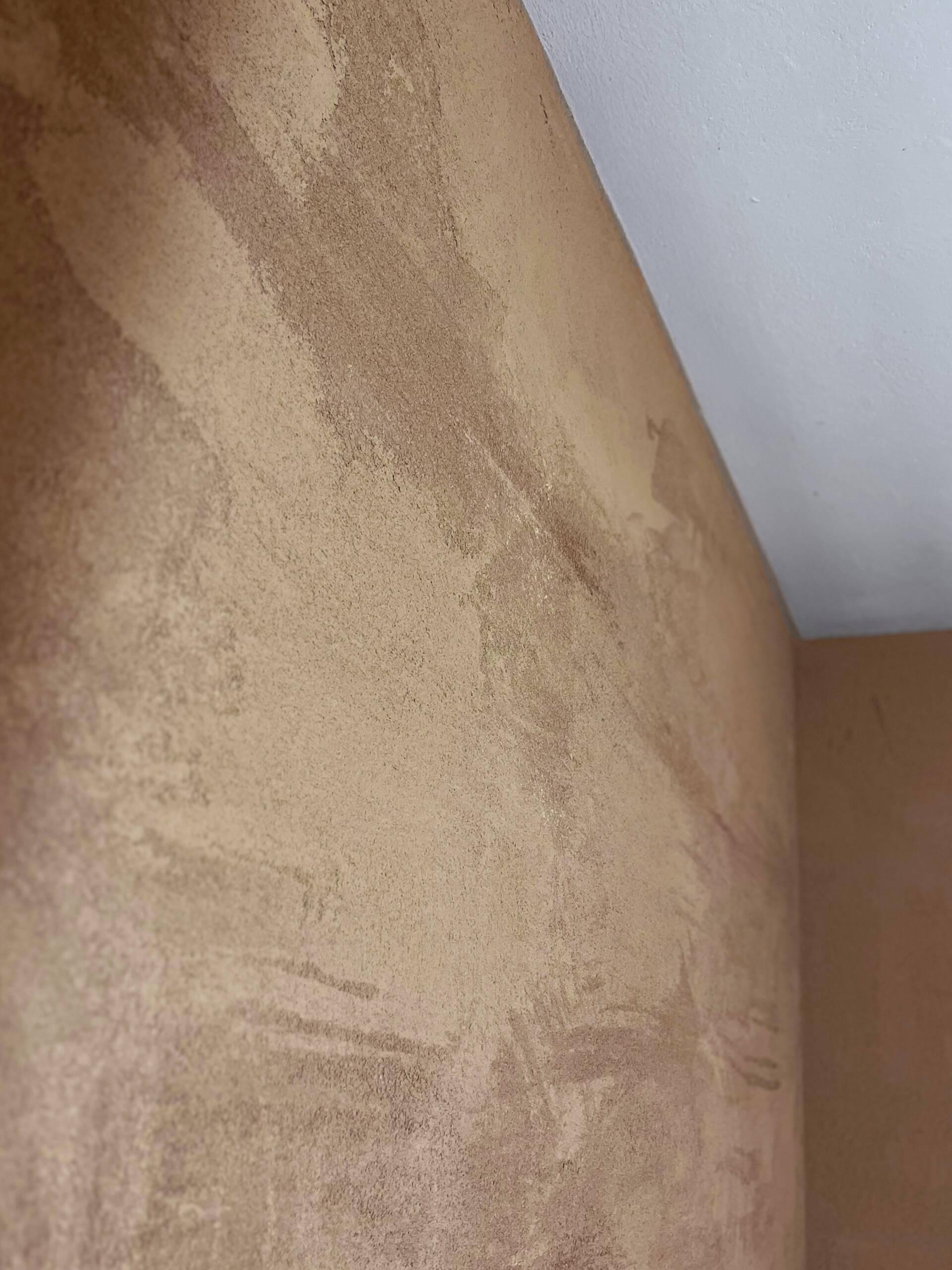 Dettaglio di una parete rifinita con intonaco in terracruda, applicato su pannelli in argilla Clayboard per un risultato naturale e traspirante.